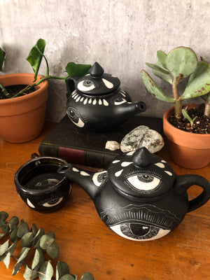 two black teapots, carved with eyes and snakes. 